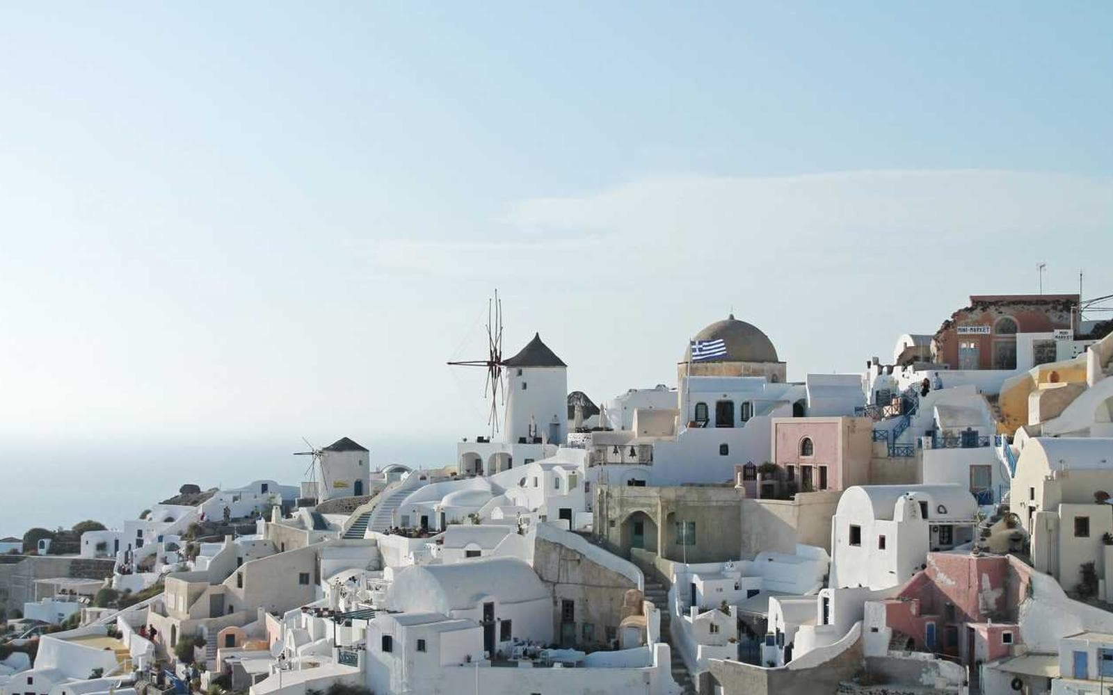 Whitewashed houses and blue-domed churches stepped down the Oia cliff above the caldera